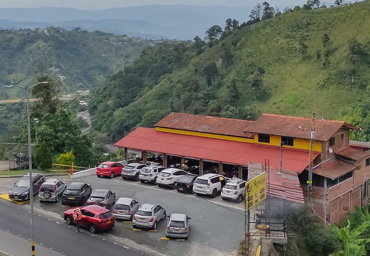 Foto real: vista aérea de la sede actual de Los Arrieros en la Autopista del Café Km. 5, rodeada de montañas y paisaje cafetero