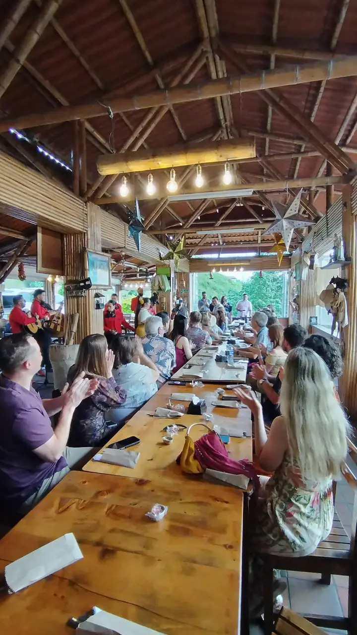 Comensales en el interior de Los Arrieros bajo el techo de guadua, con música en vivo